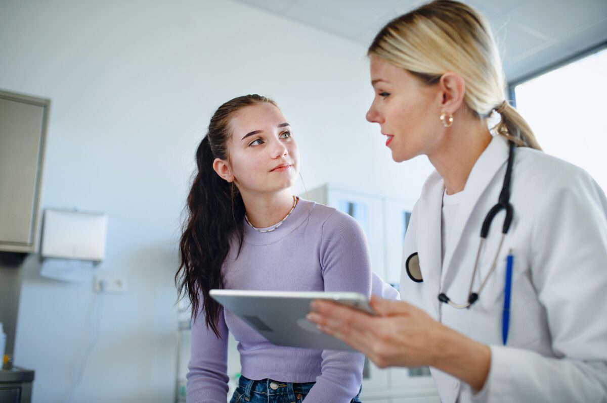Young woman doctor explaining diagnosis to teenage girl in her office.