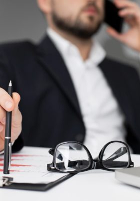 Picture of a lawyer holding a pen and a paper while being on the phone