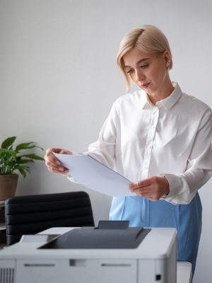 a woman looking at a piece of paper that came out of a printer