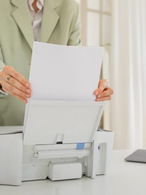 a woman putting a piece of paper into a printer using Tungsten eCopy ShareScan