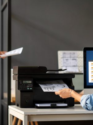 a woman sitting next to a printer on the desk