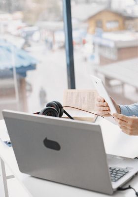 a person holding a phone to talk into while working on a laptop