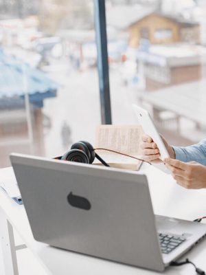 a person holding a phone to talk into while working on a laptop