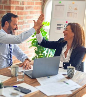 2 people behind a laptop, giving each other a highfive.