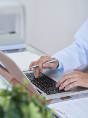 a doctor using a laptop to type patient notes