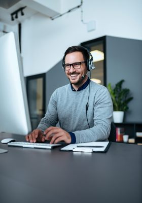 Heureux employé d'un centre d'assistance travaillant sur son ordinateur.