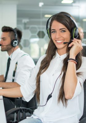 Smiling friendly female call-center agent with headset working on support hotline in the office