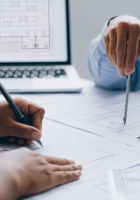 architect drawing on a blueprint on architectural project at the construction site