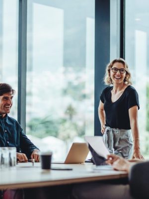 Office colleagues having casual discussion during meeting in conference room. Group of men and women sitting in conference room and smiling.