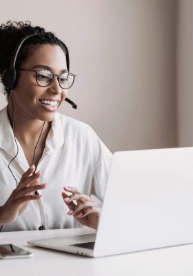 Donna che lavora con il riconoscimento vocale sul suo computer. Ha un paio di cuffie.