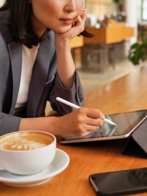 Busy young professional business woman using signdoc on tablet pad computer sitting at table in cafe.