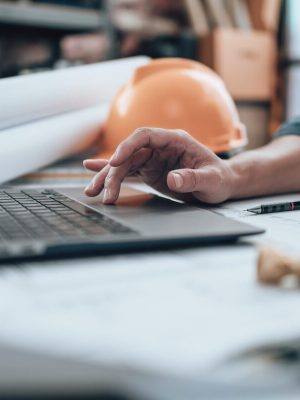 Ingénierie travaillant avec des dessins d'inspection sur ordinateur portable dans le bureau et calculatrice, règle triangulaire, lunettes de sécurité, compas, pied à coulisse sur Blueprint. Ingénieur, architecte, industrie et concept d'usine.