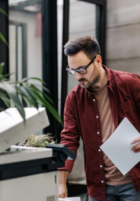 a man looking at a piece of paper coming out of the printer set up with Tungsten Capture