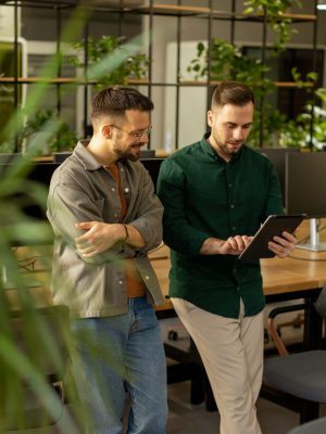Collaborative Discussion in a Modern Office With Exposed Brick Walls Two professionals are engaged in a focused conversation while holding digital tablet