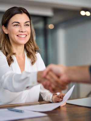 Happy mid aged business woman manager handshaking at office meeting. Smiling female hr hiring recruit at job interview, bank or insurance agent, lawyer making contract deal with client at work.