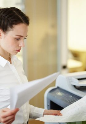 Banquier ou agent occupé à lire des documents avant d'en faire des copies sur une photocopieuse