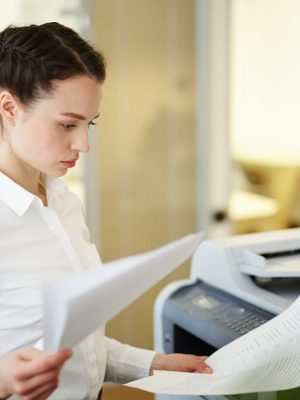 Banquier ou agent occupé à lire des documents avant d'en faire des copies sur une photocopieuse