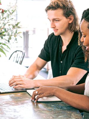 2 people behind a laptop, helping each other