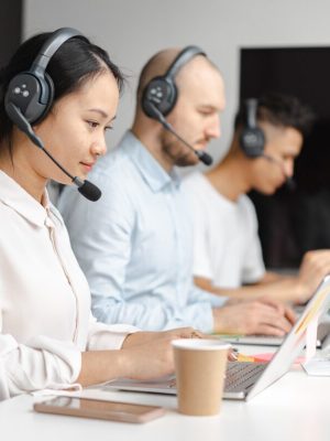 3 Personen in einem Büro, die mit Headsets arbeiten