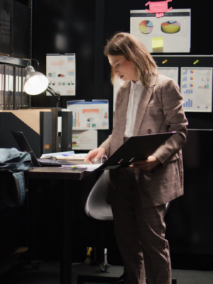 a woman in a suit holding a folder standing next to a computer