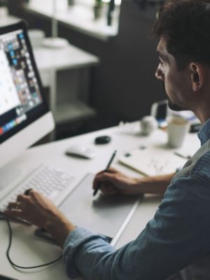 Modern designer sitting in front of computer and working in office. using Enfocus Pitstop